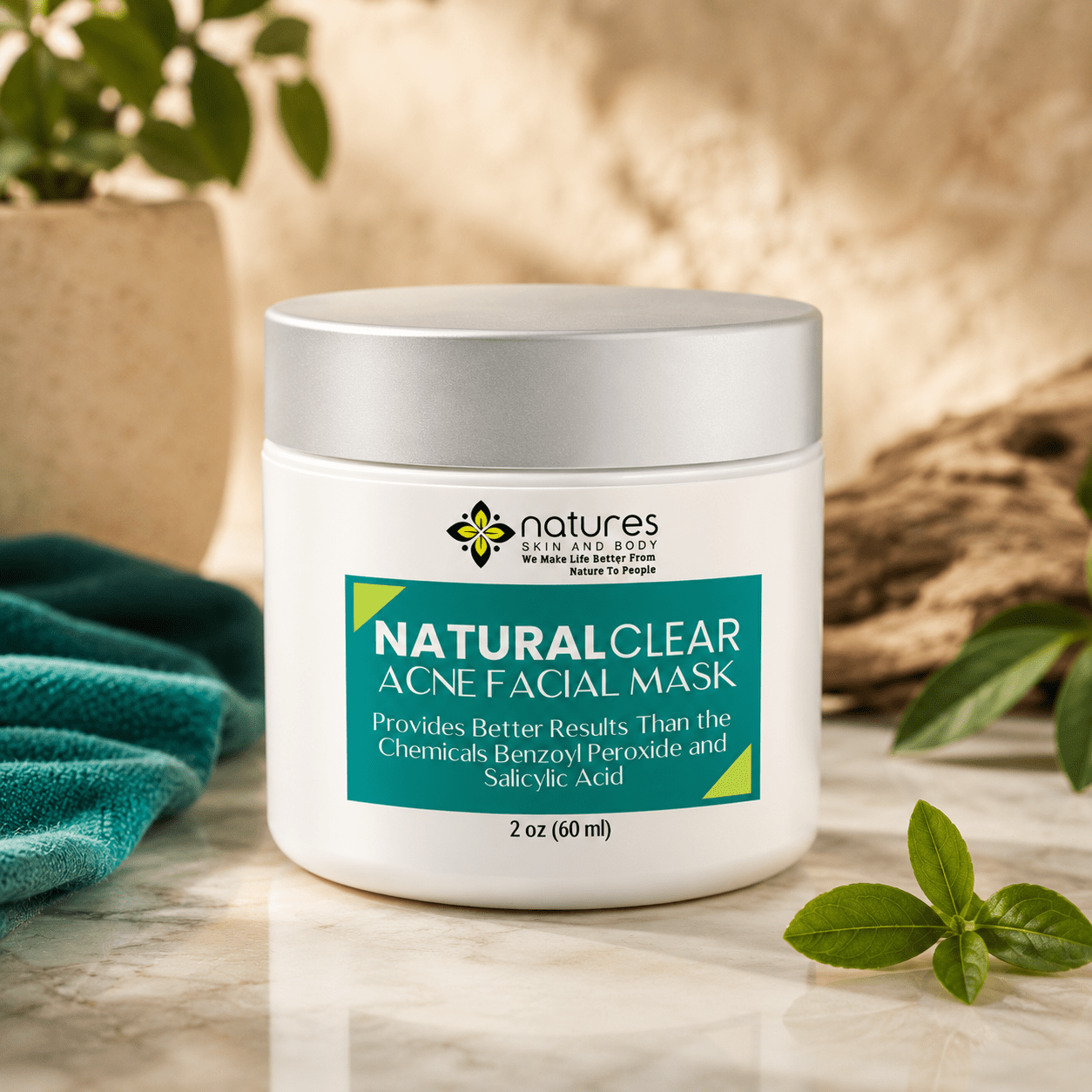 White jar with silver lid containing green acne facial mask on marble surface with greenery and towel
