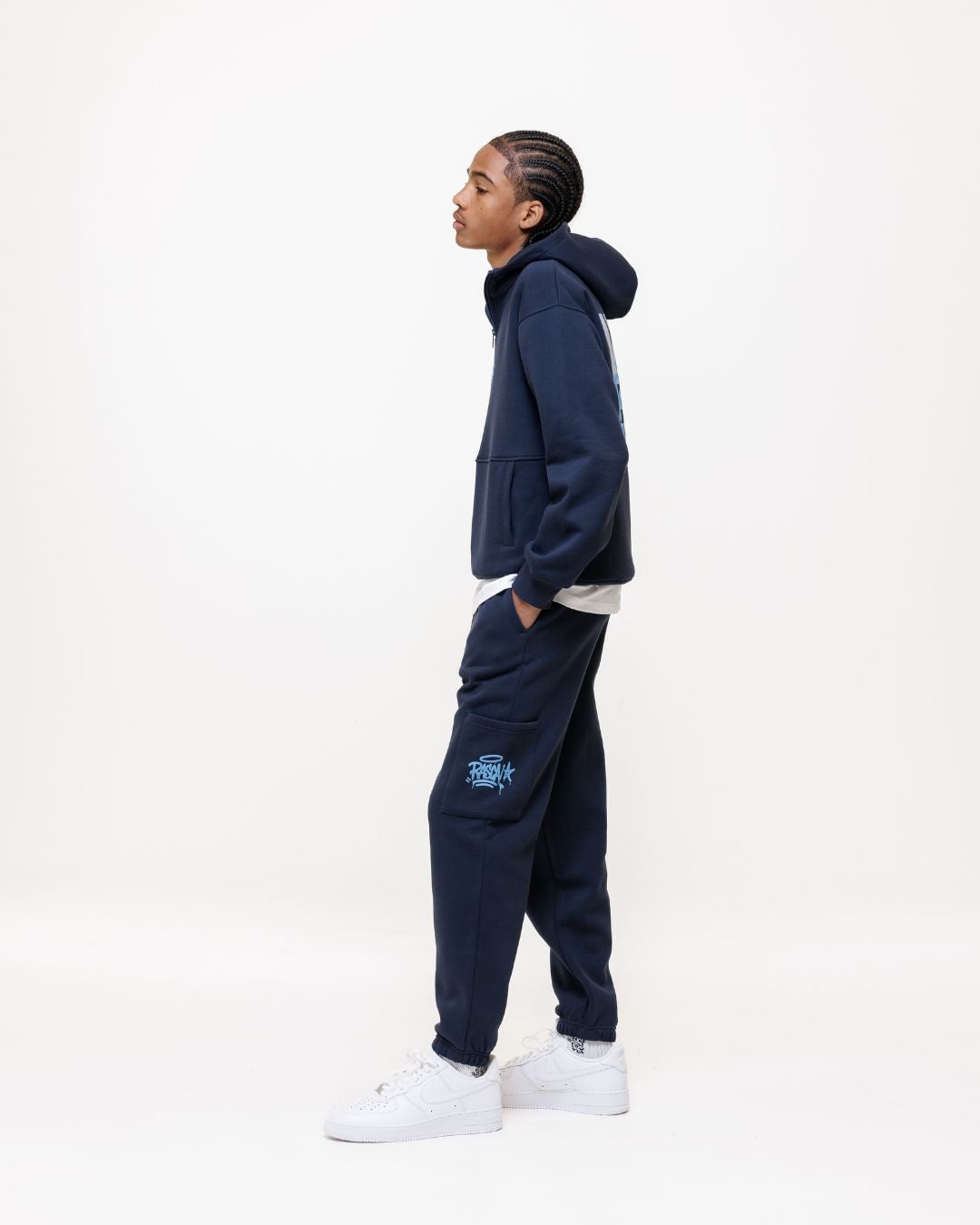 Side profile of person wearing navy zip hoodie and matching cargo pants with white sneakers