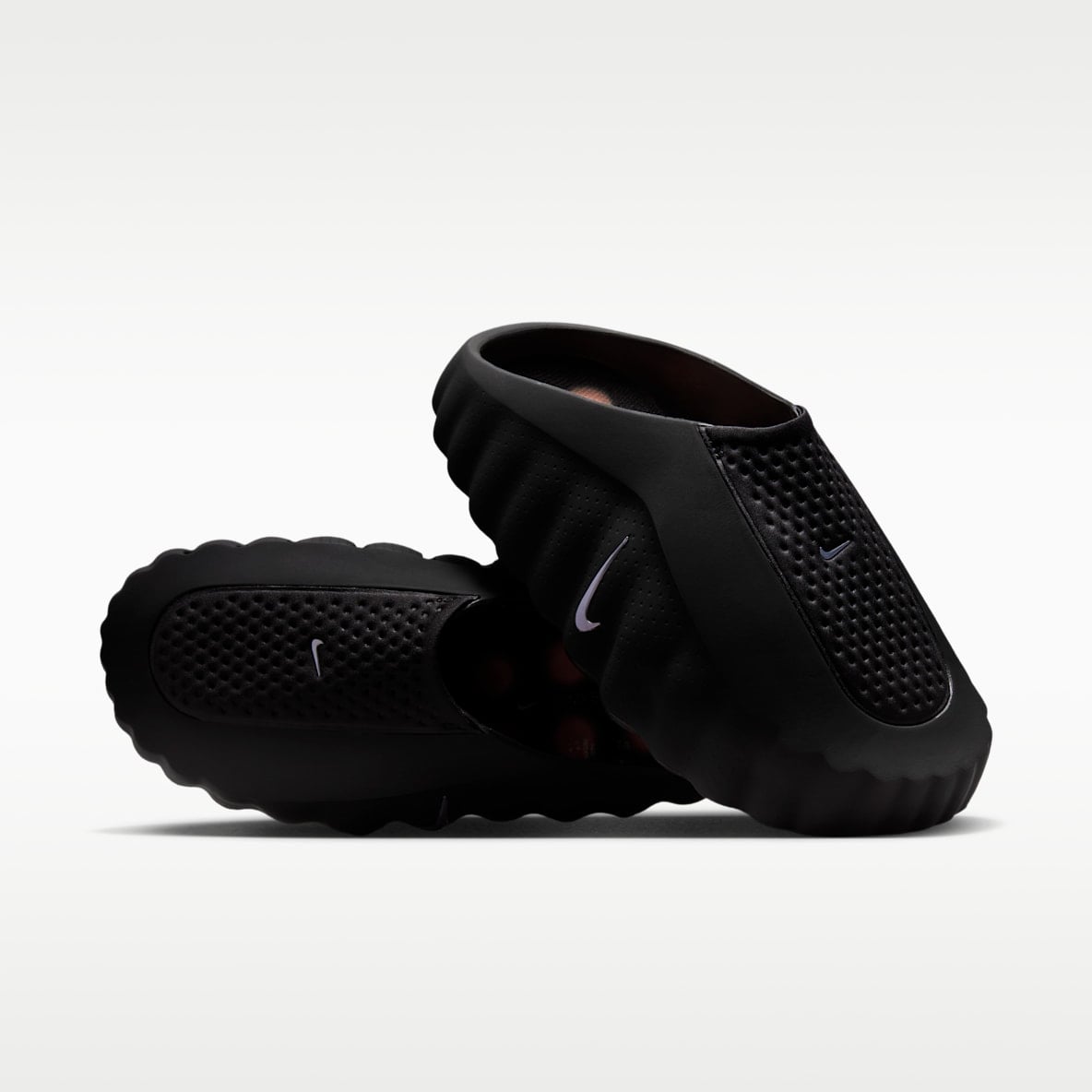 Black slide sandals with textured footbed shown from angled side view