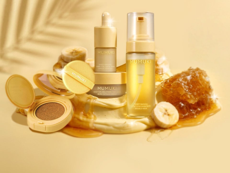 Golden-themed skincare collection featuring cushion compacts, serums, ampoules, and creams with honey and banana ingredients on a beige background